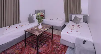 a room with two beds and a table with a vase of flowers at Hotel Riad Fantasia in Marrakech
