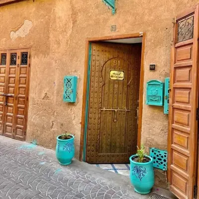 a building with two blue pots in front of a door at Riad 1001 couleurs in Marrakech