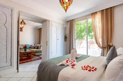 a bedroom with a bed and a living room at Hotel Akabar in Marrakech