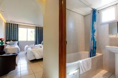 a bathroom with a bath tub and a bedroom at Hotel Akabar in Marrakech