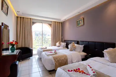 a hotel room with three beds and a window at Hotel Akabar in Marrakech