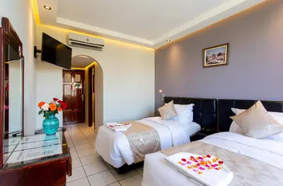 a hotel room with two beds and a flat screen tv at Hotel Akabar in Marrakech
