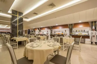 a restaurant with white tables and chairs and two chefs at Pickalbatros Aqua Fun Club All Inclusive in Marrakech