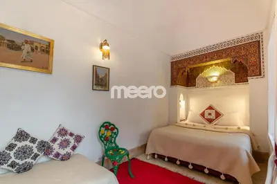 a hotel room with two beds and a chair at Riad Zineb in Marrakech