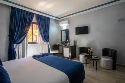a hotel room with a bed and a desk and a window at Hotel Meriem Marrakech in Marrakech