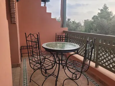 a table and chairs on a balcony with a window at Palmeraie village 2 , les jardins de la palmeraie 2 in Marrakech