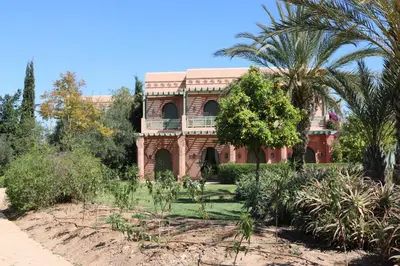 a brick house with a palm tree in front of it at Palmeraie village 2 , les jardins de la palmeraie 2 in Marrakech