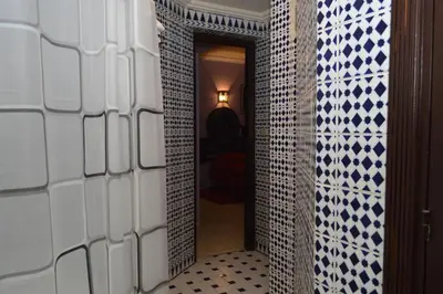a hallway with blue and white tiled walls and a mirror at Hotel Amalay in Marrakech