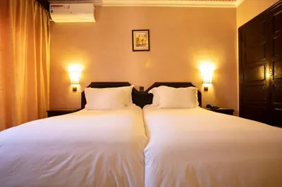two beds in a hotel room with white sheets at Diwane Hotel & Spa Marrakech in Marrakech