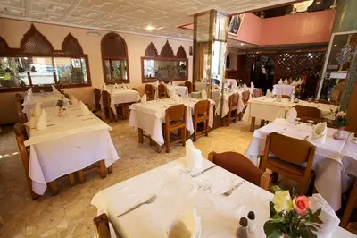 a restaurant with white tables and chairs with flowers on them at Hotel Tachfine in Marrakech