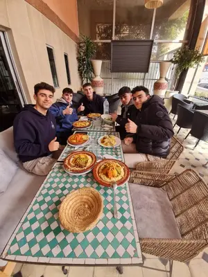 a group of people sitting around a table with food at Hotel Tachfine in Marrakech