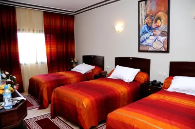 a room with three beds and a painting on the wall at Residence Hotel Assounfou in Marrakech