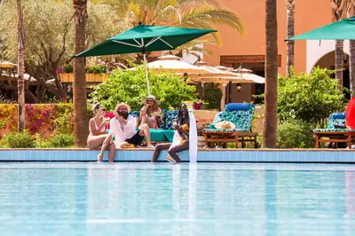 a group of people sitting on the edge of a swimming pool at Jaal Riad Resort Adults Only in Marrakech