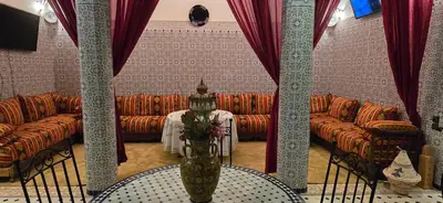 a room with couches and a table with a vase with flowers at Riad Raffaa in Marrakech