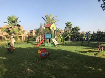 a park with a playground with a slide and swings at Magnifique Appt Atlas Golf Resort Marrakech in Marrakech