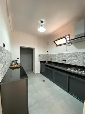 a large kitchen with black cabinets and tile walls at Villa des Roses Privée in Marrakech