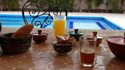 a table with two glasses of orange juice and some drinks at Villa des Roses Privée in Marrakech
