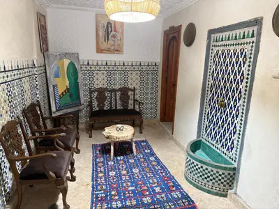 a living room with chairs and a table and a room with aarijavascript at Riad Sarsar Dar dmana in Marrakech