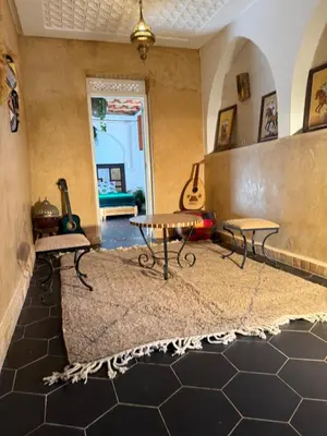 a living room with a table and guitars on the wall at Riad Sarsar Dar dmana in Marrakech