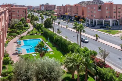 a city street with a pool and palm trees at Majorelle family residence in Marrakech