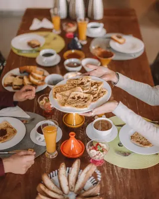 a group of people sitting around a table with food at Villa YENMOZ en exclusivité avec piscine privée dans la Palmeraie in Douar Caïd Layadi