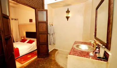 a bathroom with a sink and a bedroom with a bed at Riad Elias & Spa in Marrakech