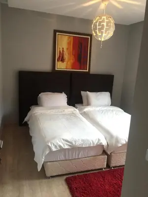 a bedroom with two beds with white sheets and a chandelier at prestigia in Marrakech