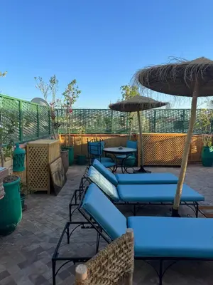 a patio with blue chairs and umbrellas and tables at Riad Zahri in Marrakech