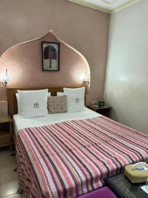 a hotel room with a bed with a striped blanket at Riad Zahri in Marrakech