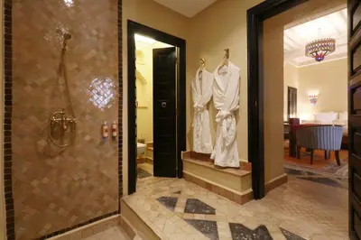 a bathroom with a shower and two dresses on hangers at Riad Omara al Kasbah in Marrakech