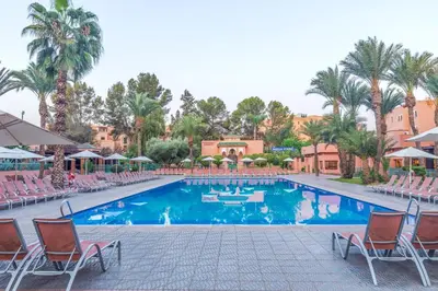 a pool at a resort with chairs and palm trees at Rose Aqua Park Hotel in Marrakech