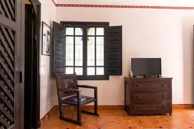 a room with a chair and a television and a dresser at Maison Ayda in Marrakech