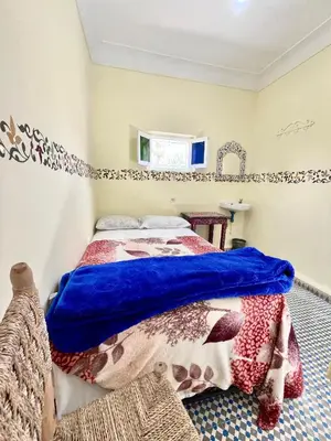 a bedroom with a bed with a blue comforter at Hotel Medina in Marrakech