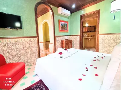 a bedroom with a white bed and a red chair at Riad la villa bleue & SPA in Marrakech