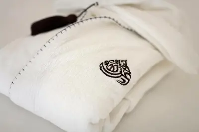 a white towel with a black emblem on it at Dar Rhizlane, Palais Table d'hôtes & SPA in Marrakech