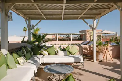 a patio with green and white couches and a table at Dar Lalla F'dila in Marrakech