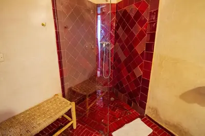 a red tiled shower with a bench in a bathroom at Riad Les Jardins des Lilas in Marrakech