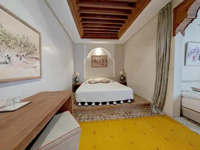 a bedroom with a white bed and a desk at Riad Slitine & Spa in Marrakech