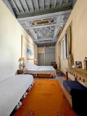 a bedroom with two beds and an orange rug at Riad Slitine & Spa in Marrakech