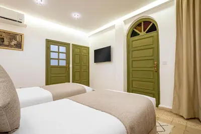 two beds in a hotel room with green doors at Riad Hamdane Rooftop & SPA in Marrakech