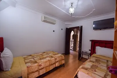 a bedroom with two beds and a flat screen tv at Riad Assia in Marrakech