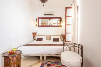 a bedroom with a bed with a mirror and a chair at Riad Amira in Marrakech