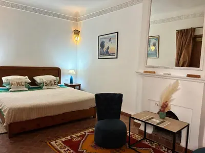 a bedroom with a bed and a chair and a mirror at Riad Chameau FDC Hôtel SPA in Marrakech
