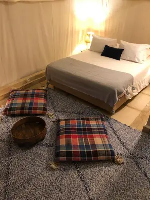 a bedroom with a bed and two pillows on a rug at Manzil La Tortue in Douar Caïd Layadi