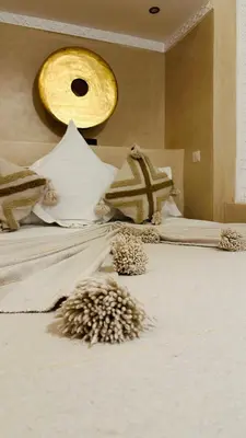 a bed with white sheets and pillows with a yellow light at Riad Dar Ten in Marrakech