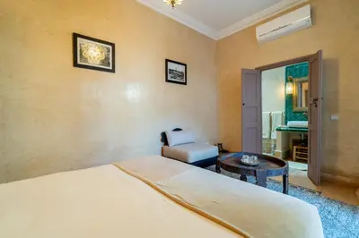 a bedroom with a bed and a chair and a table at Riad Beldi in Marrakech