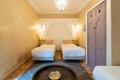 a room with two beds and a table at Riad Beldi in Marrakech