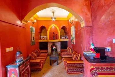 a living room with orange walls and chairs and a fireplace at Riad Mboja Chez Ali Baba in Marrakech