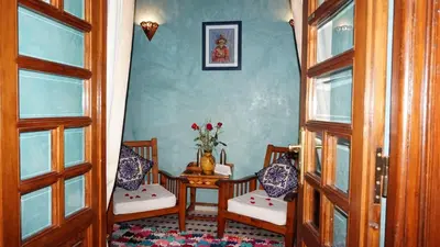 a room with two chairs and a table with a vase of flowers at Riad Samsli in Marrakech