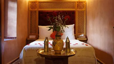 a bedroom with a bed with a vase of flowers on a table at Riad Samsli in Marrakech